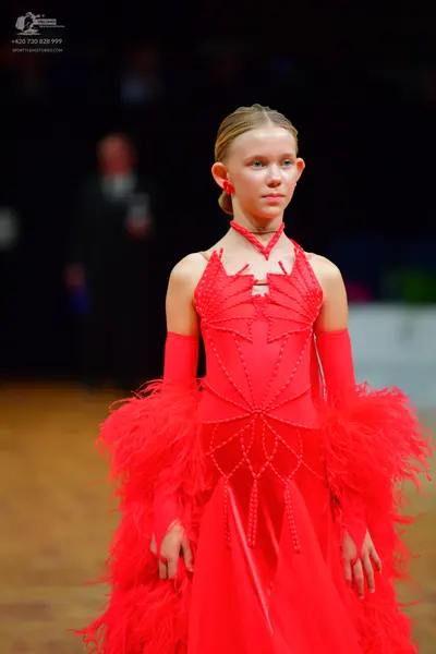 Dancesport competitor: Female dancer: red latin dress with bead/sequin patterns and feathers/fringe, an