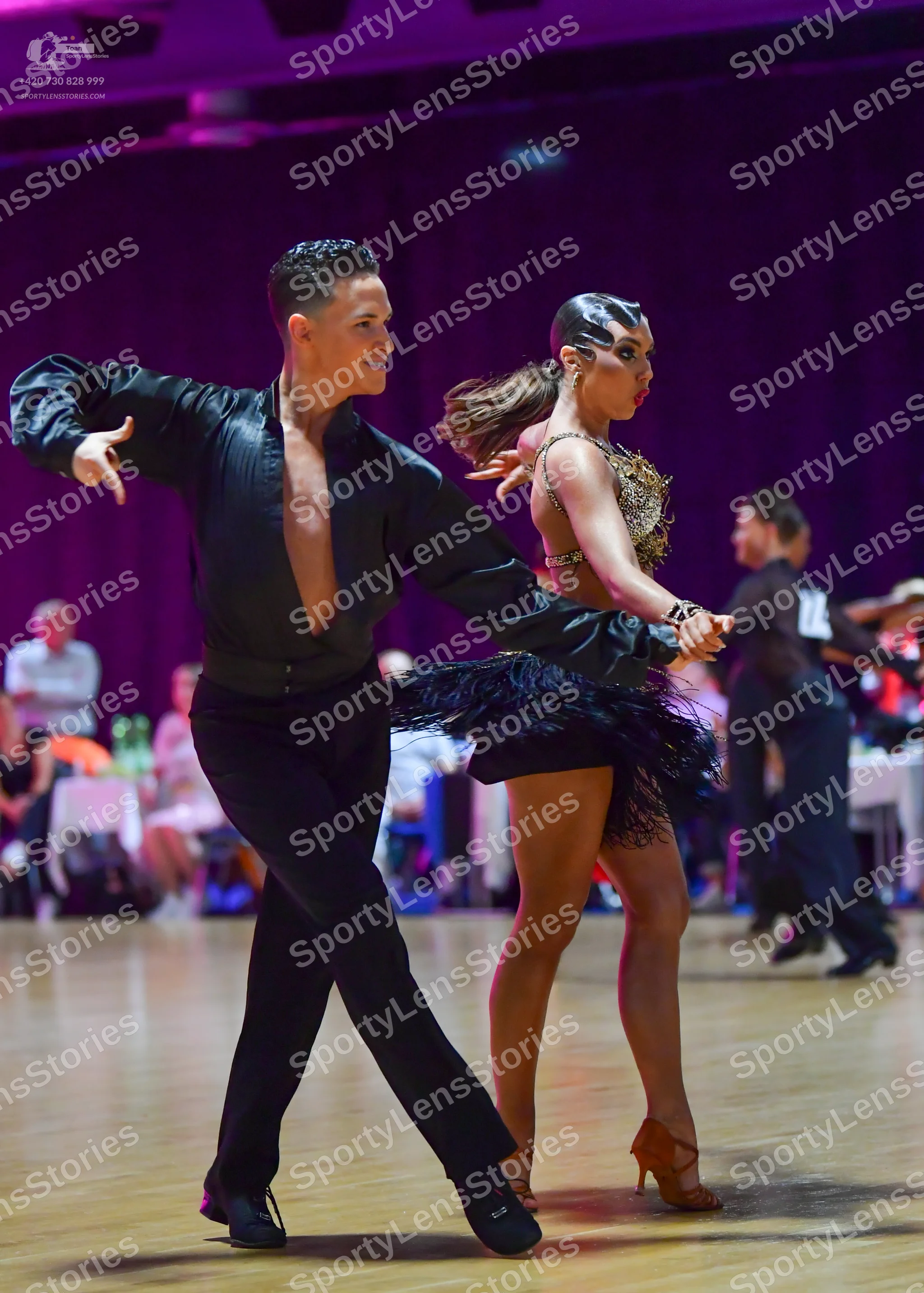 Dancesport competitor: Male dancer (foreground): black long-sleeved shirt, open at the chest, with blac