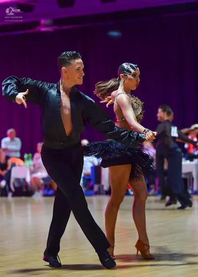 Dancesport competitor: Male dancer (foreground): black long-sleeved shirt, open at the chest, with blac