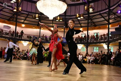 Dancesport competitor: Male dancer (foreground): black long-sleeved shirt and black trousers