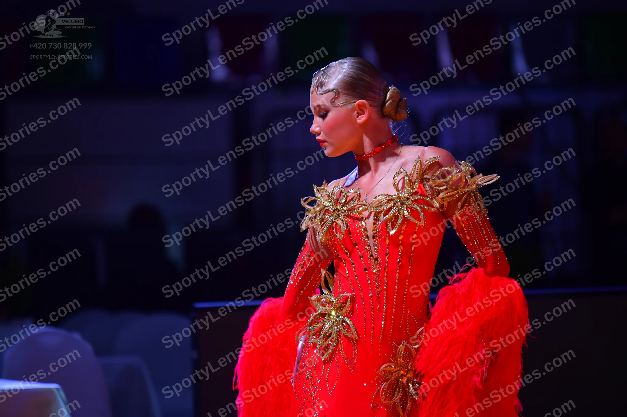 Dancesport competitor: Female dancer: red Latin dress with gold floral embellishments and large red ruf