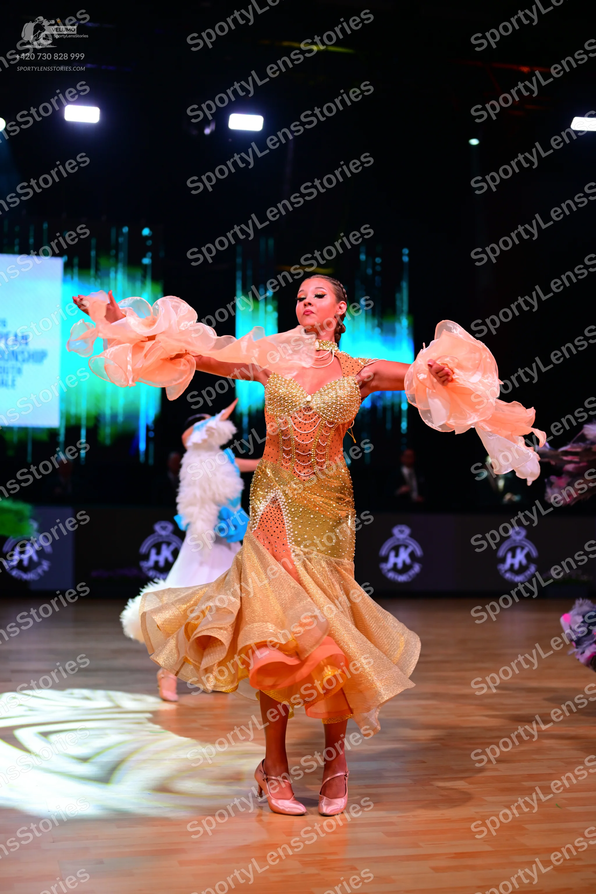 Dancesport competitor: Female dancer: gold latin dress with a sequined bodice and voluminous, ruffled,