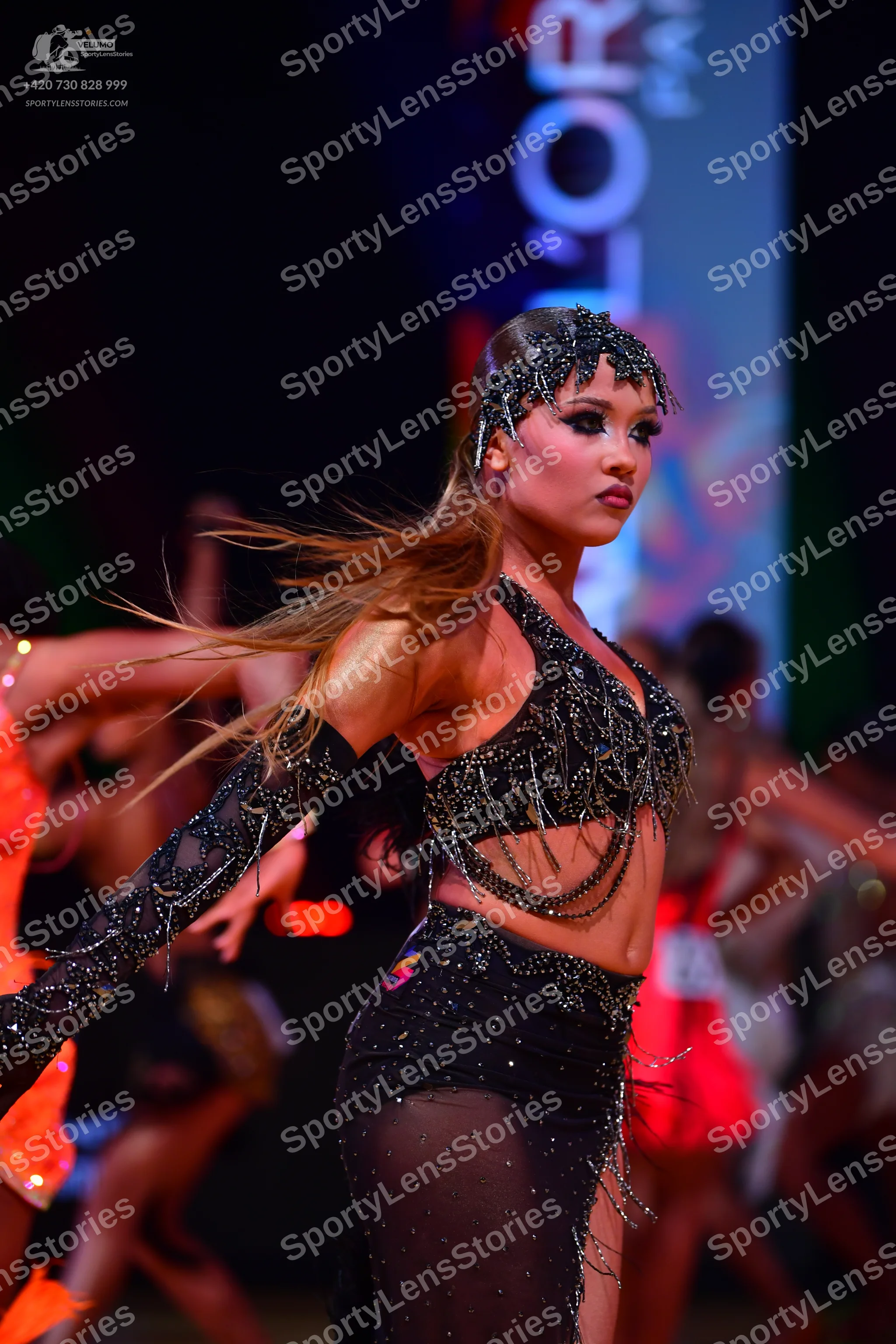 Dancesport competitor: Main dancer: black latin costume consisting of a crop top and skirt heavily embe
