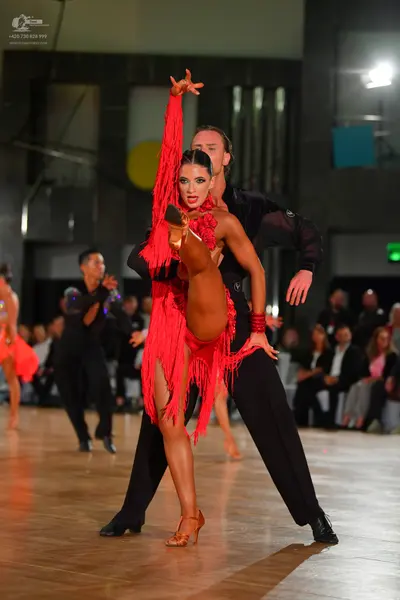Dancesport competitor: Central female dancer: red latin dress with long fringe and red and gold bracele