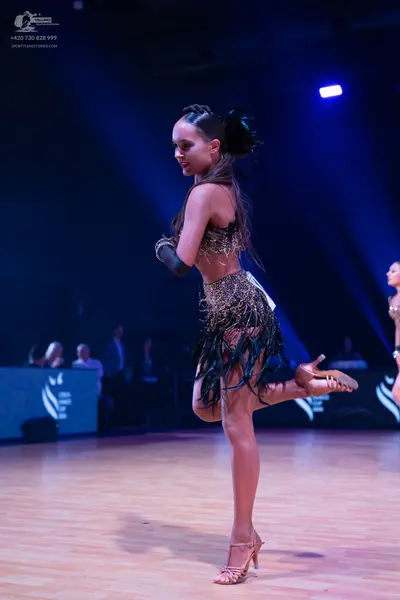 Dancesport competitor: Female dancer: dark, sequined Latin dance costume with a long black fringe skirt