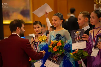 Dancesport competitor: Male dancer in foreground: maroon suit jacket