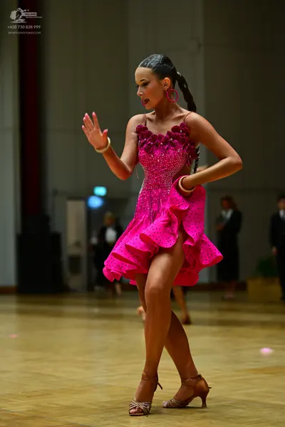Dancesport competitor: Female dancer: bright pink latin dance dress with a sequined bodice and a ruffle