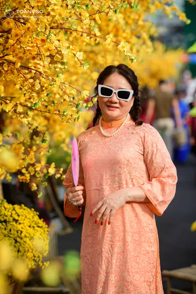 Dancesport competitor: Female dancer: peach-colored long-sleeved Áo dài with a subtle floral pattern, a