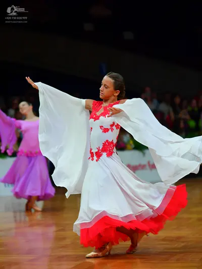 Dancesport competitor: Female dancer in foreground: white ballgown with red lace bodice and red hem, fe