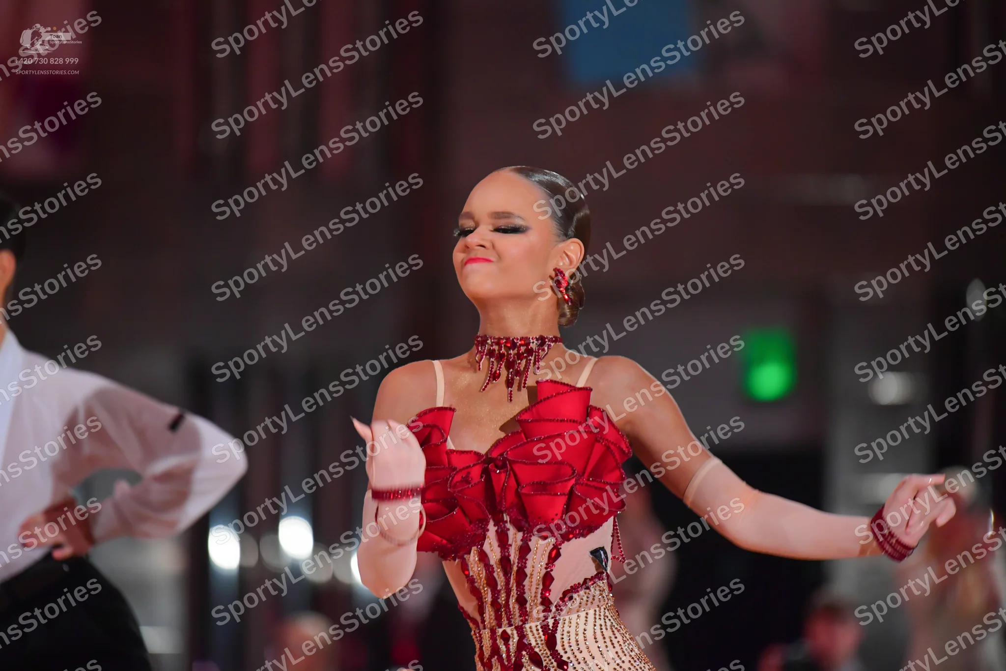 Dancesport competitor: Female dancer: red latin dress with large red fabric flowers, nude-colored bodic