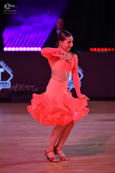 Dancesport competitor: Female dancer: peach Latin dance dress with long sleeves and a voluminous, ruffl