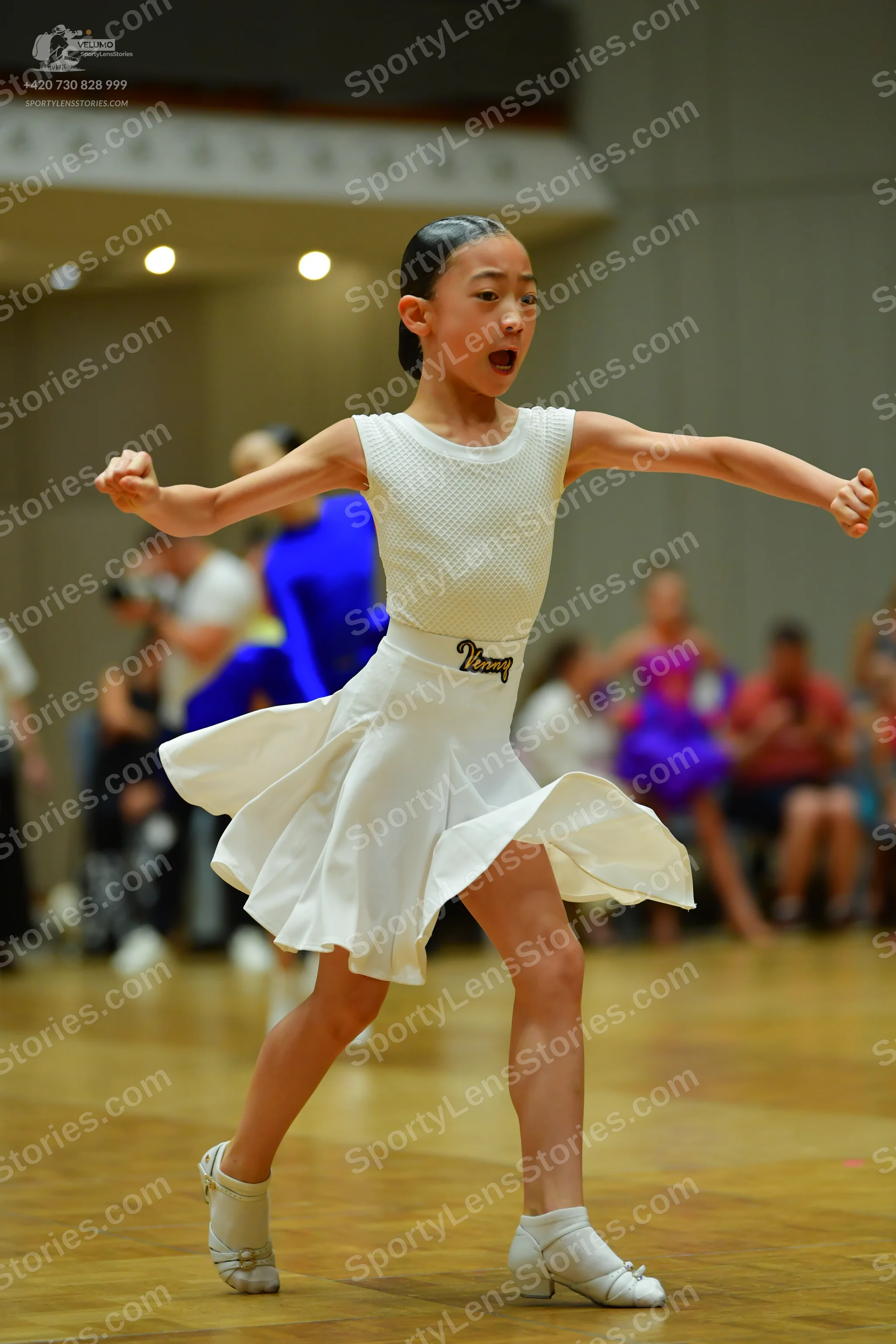 Dancesport competitor: Female dancer in foreground: white latin dress with a textured bodice and a flar
