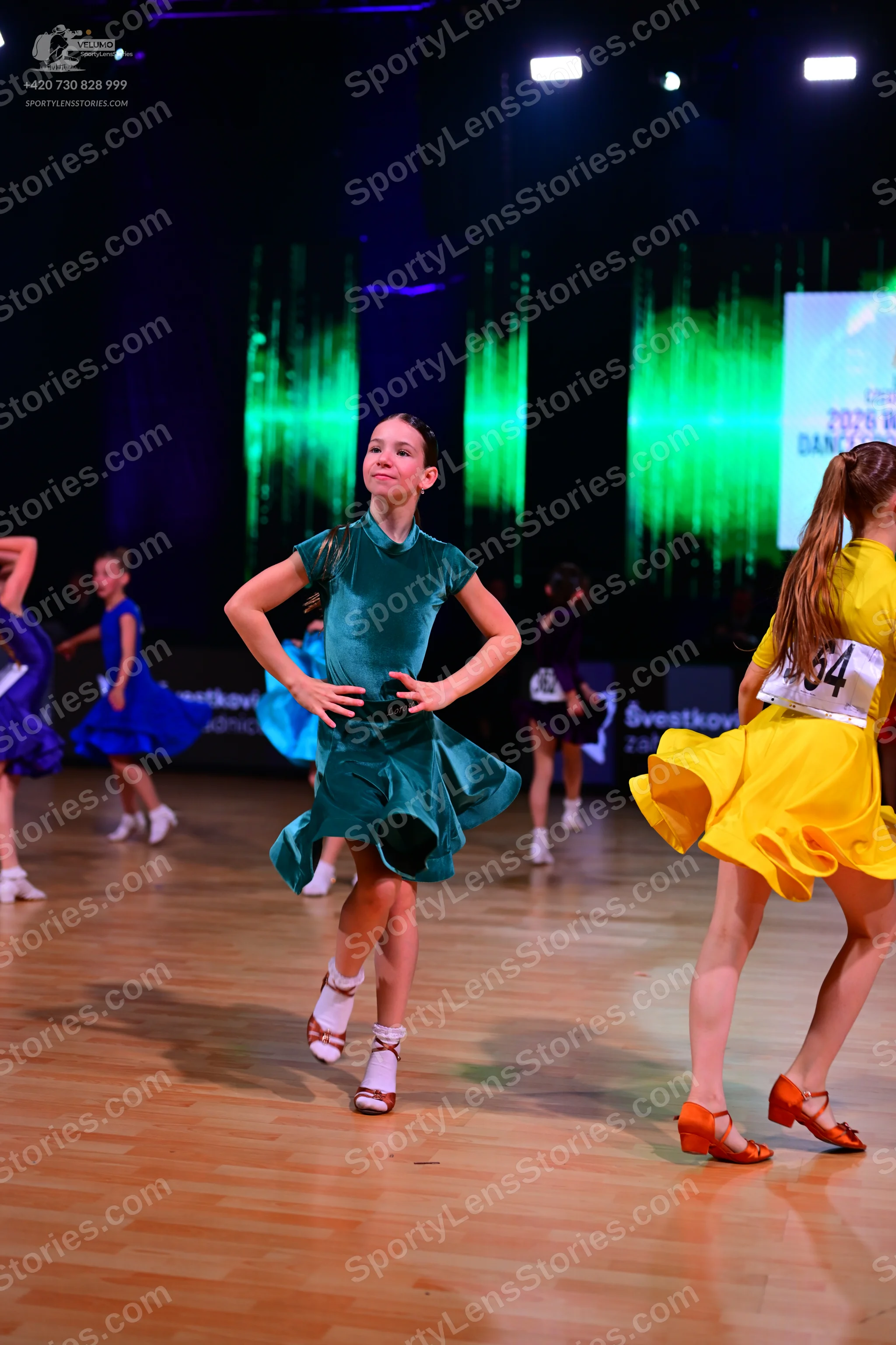Dancesport competitor: Female dancer: teal satin latin dress with short sleeves; Female dancer: yellow 