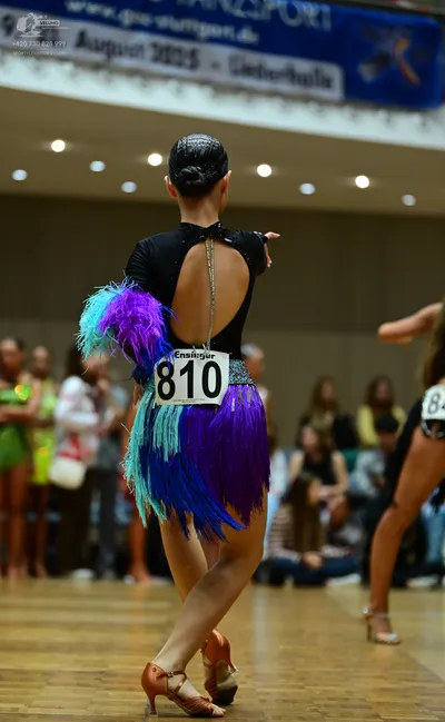 Dancesport competitor #810: **  She's wearing a dark purple/navy blue dress with a dramatic, layered skirt