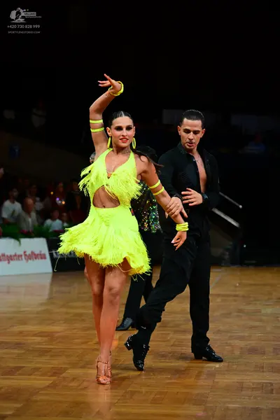 Dancesport competitor: Female dancer: neon yellow Latin dress with fringe, midriff cutout, and matching