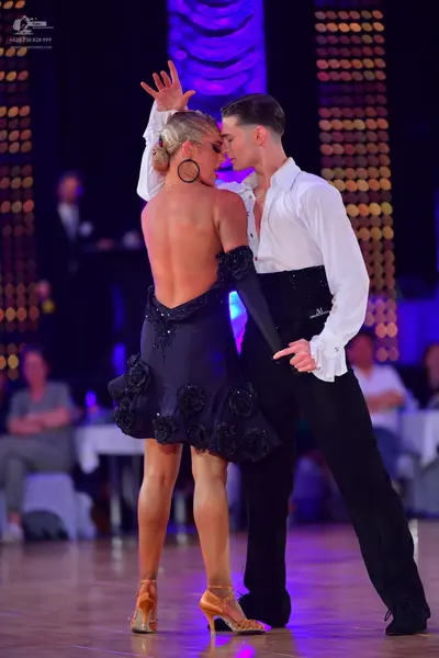 Dancesport competitor: Female dancer: backless dark navy/black Latin dress with 3D floral embellishment