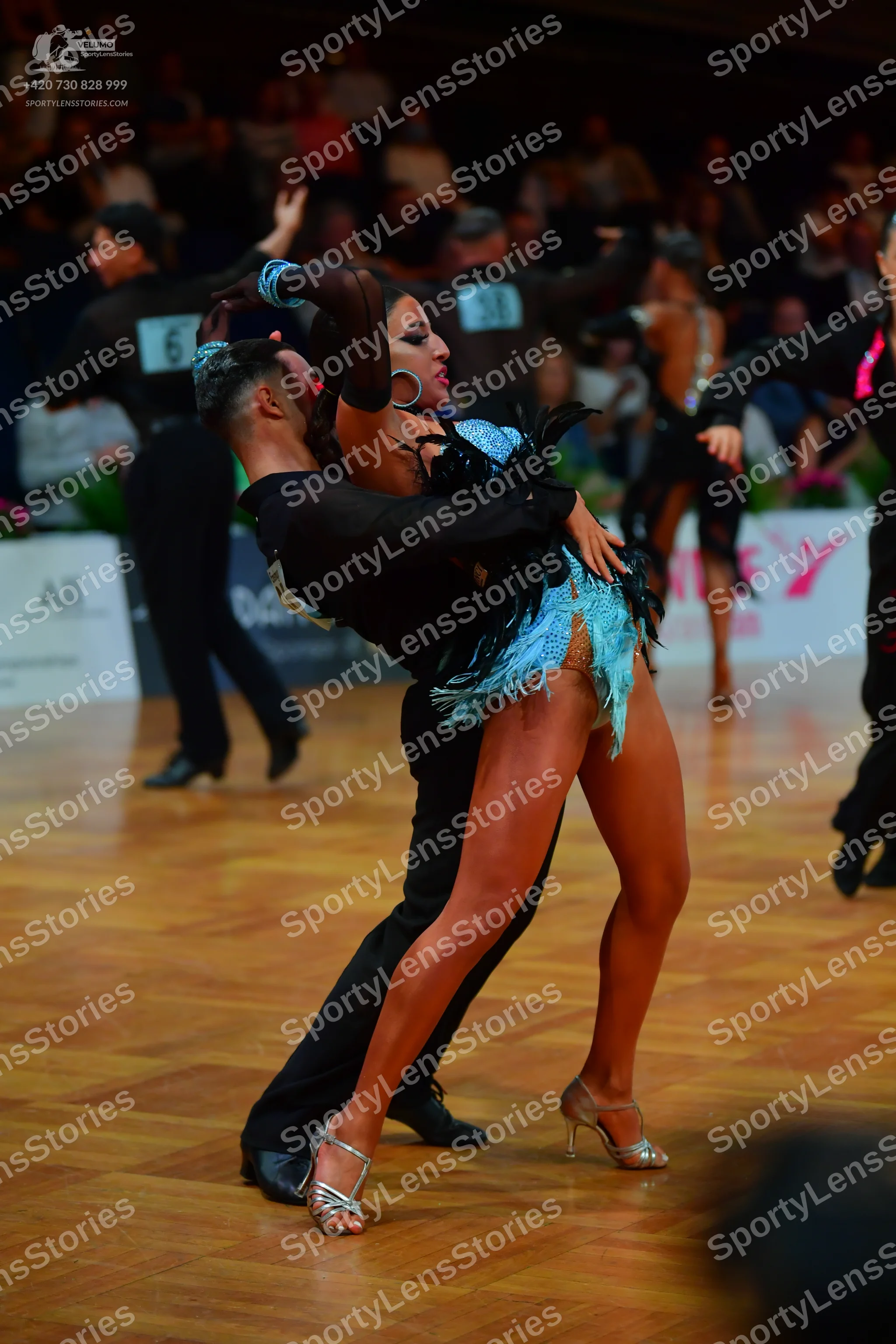 Dancesport competitor: Female dancer: light blue Latin dress with fringe and dark feather embellishment