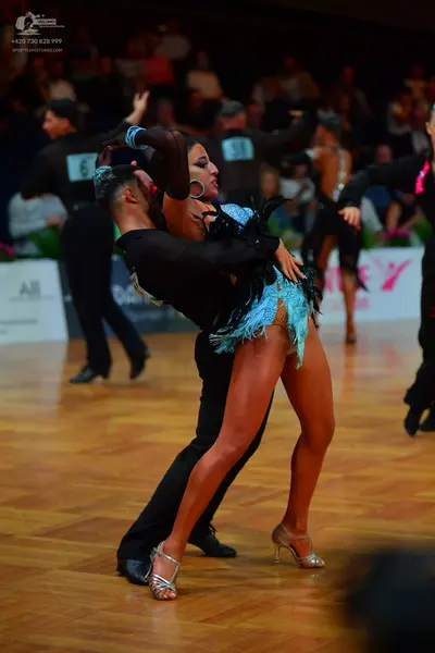 Dancesport competitor: Female dancer: light blue Latin dress with fringe and dark feather embellishment