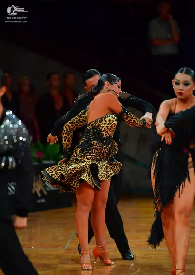 Dancesport competitor: Female dancer in center: leopard print Latin dance dress with long sleeves, blac