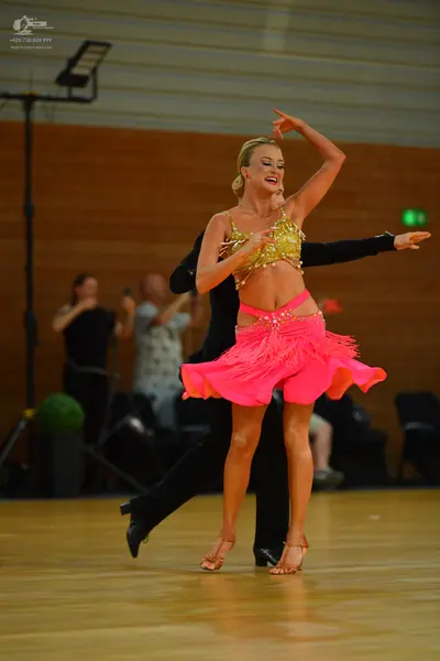 Dancesport competitor: Female dancer: gold sequin crop top and pink fringed skirt