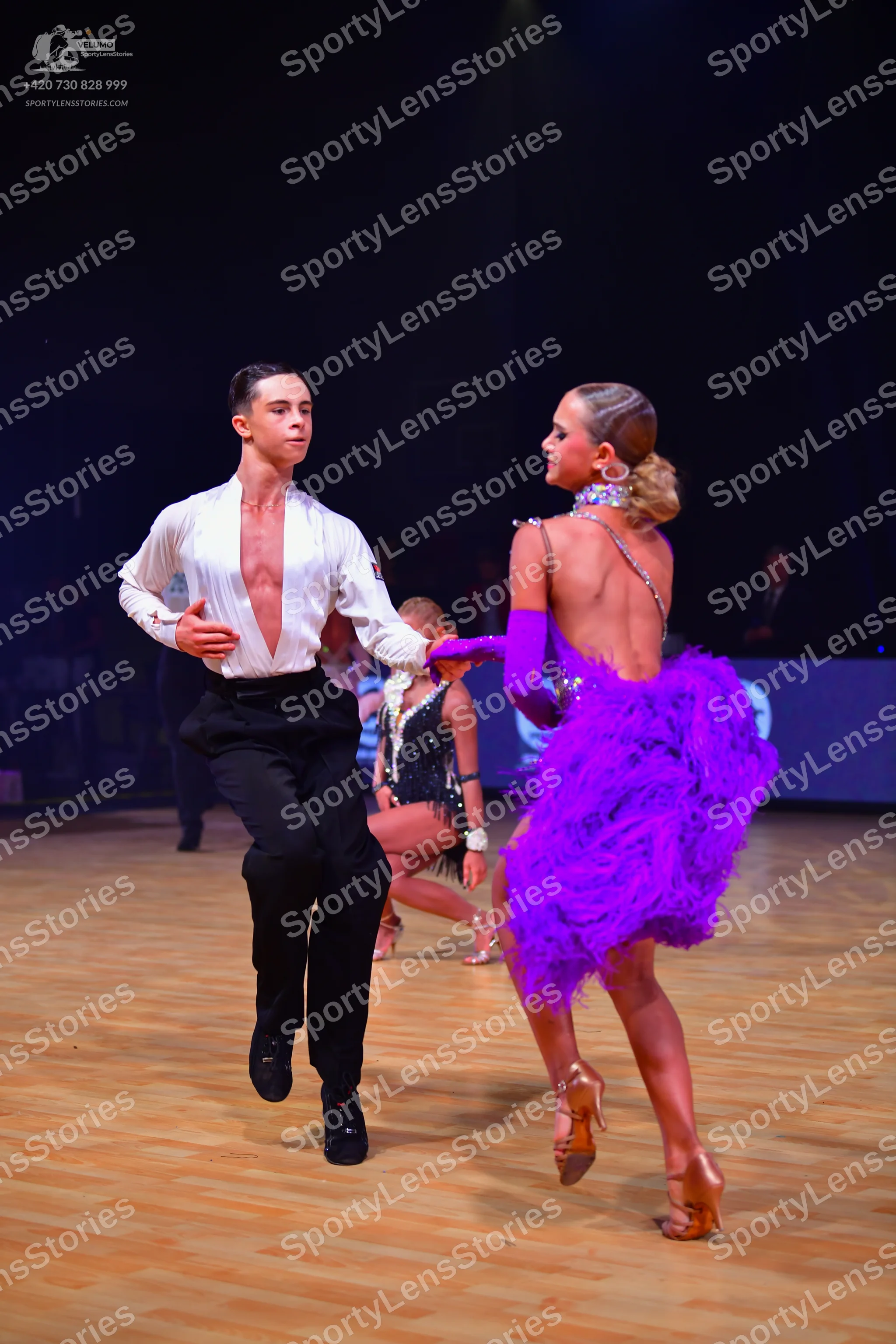 Dancesport competitor: Male dancer: white long-sleeved shirt open at the chest, black trousers, and bla