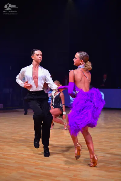 Dancesport competitor: Male dancer: white long-sleeved shirt open at the chest, black trousers, and bla