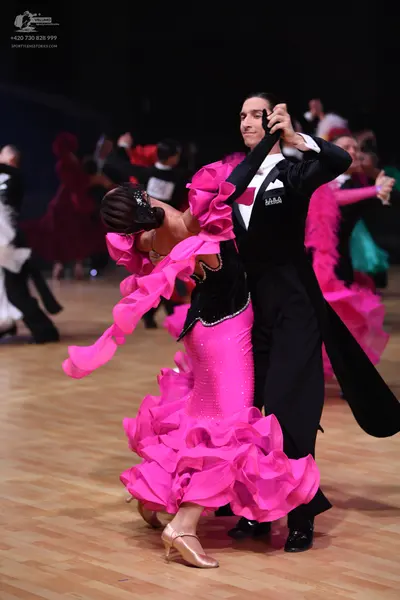 Dancesport competitor: Female dancer: bright pink latin dress with large ruffles on the skirt and sleev