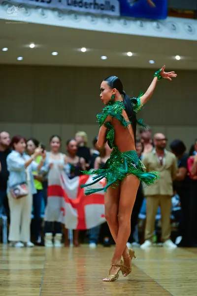 Dancesport competitor: Female dancer: emerald green latin dress with sequins and fringe, backless style