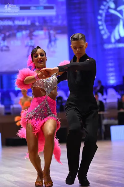 Dancesport competitor: Female dancer: bright pink Latin dance dress with a silver sequined bodice and l
